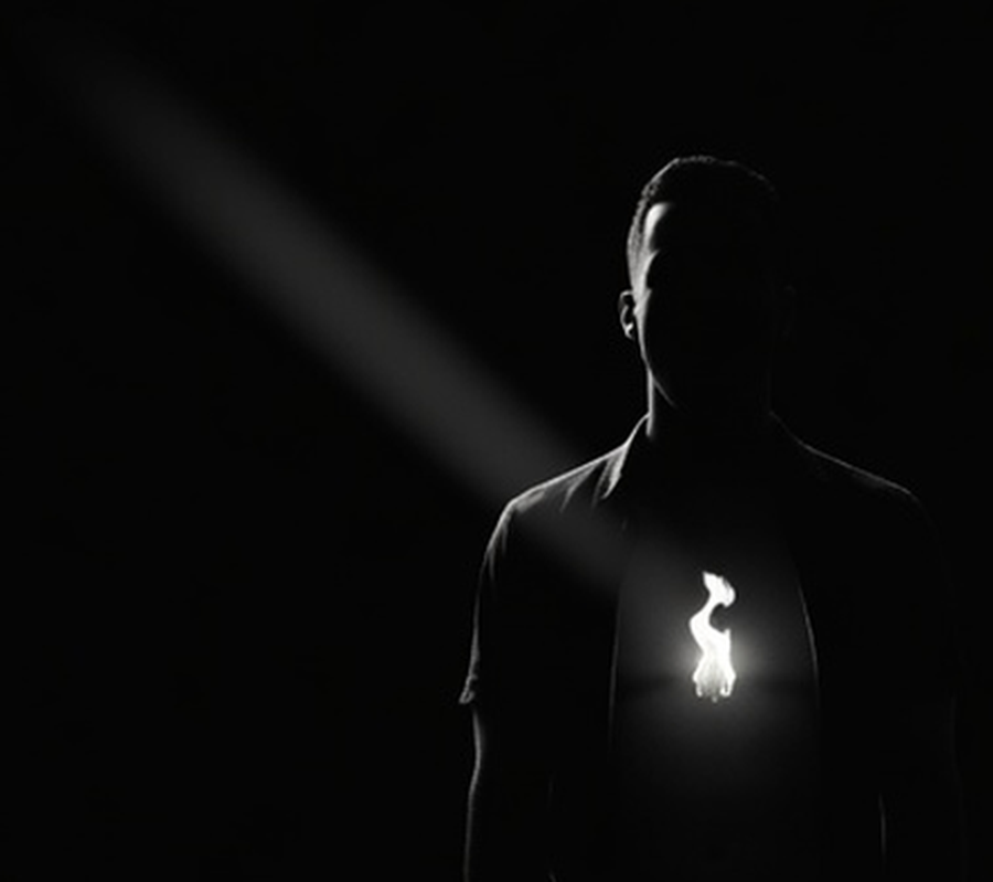 A lone silhouette with a single bright spark glowing in the chest.